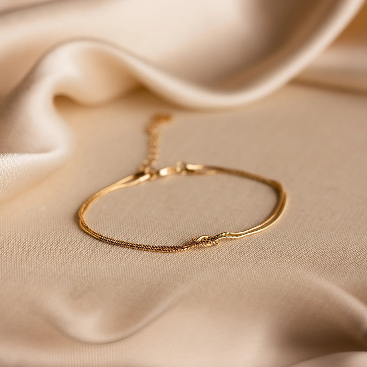 Gold Forever Knot Bracelet on cream fabric