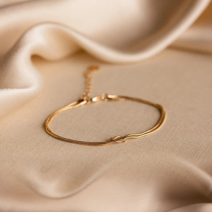 Gold Forever Knot Bracelet on cream fabric