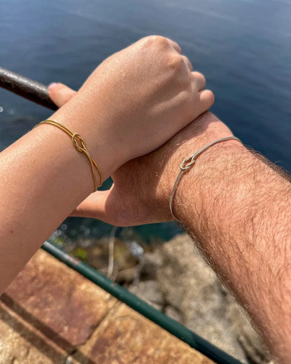 A couple wearing matching Forever Knot Bracelets outdoors