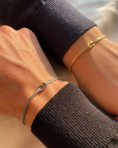 Matching Gold and Silver knot bracelets worn on two wrists